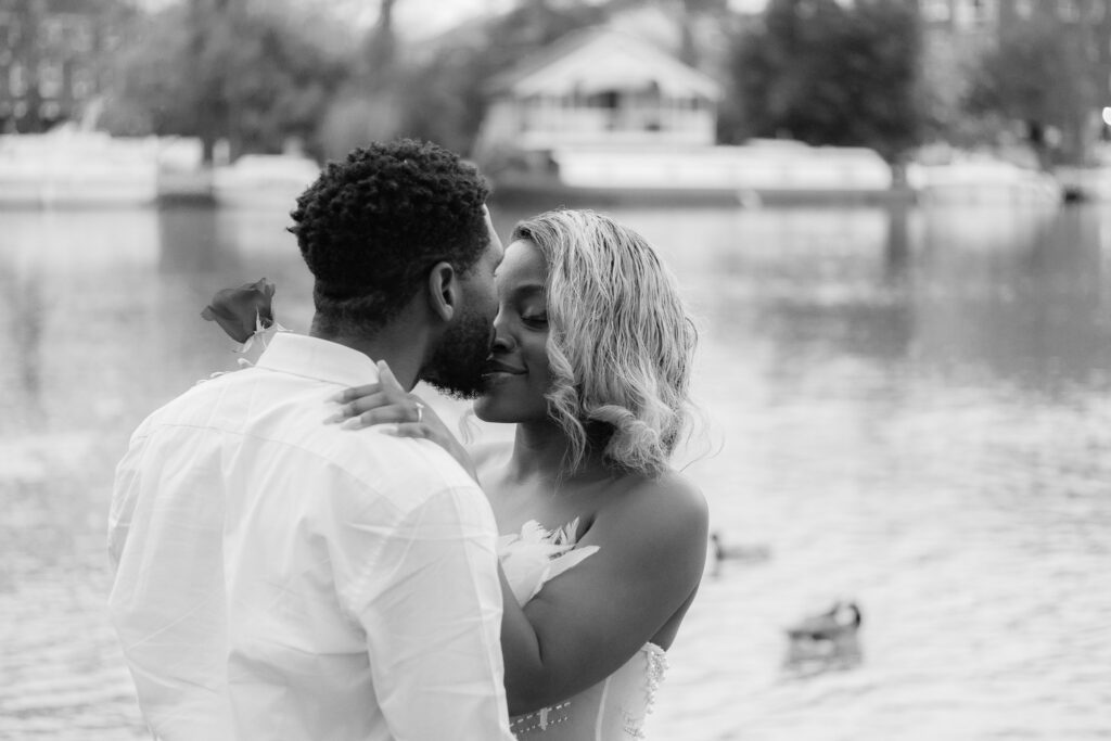Couple in love by the river, man kissing on his fiancé nose, enjoying time together while taking an engagement photoshoot