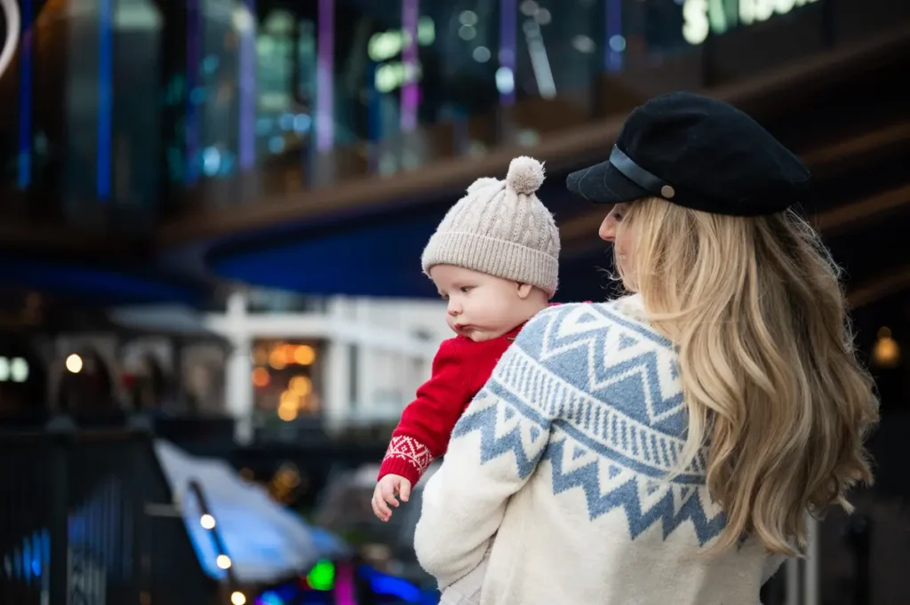 Mum holding her baby boy, both adorned in a warm sweater and hat, capturing a sweet and intimate scene.